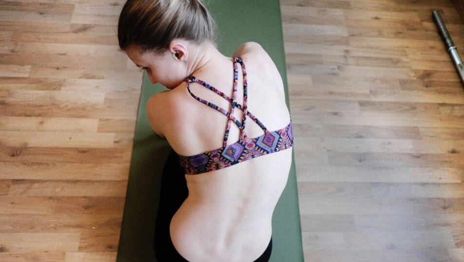 Woman in yoga pose on mat, wearing a colorful sports bra.